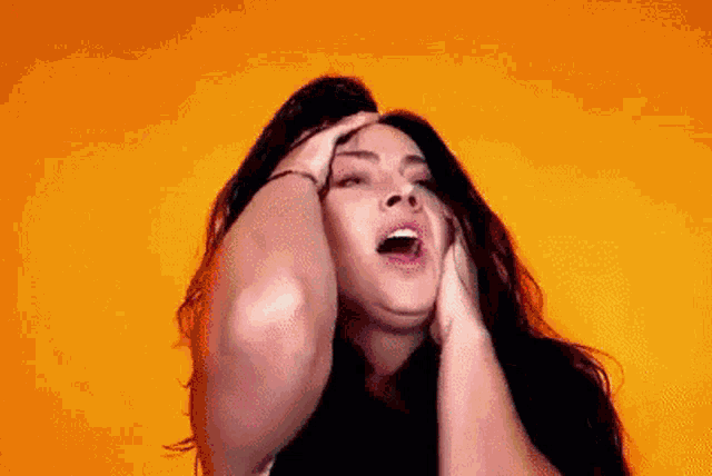 a woman is holding her head in her hands and screaming .
