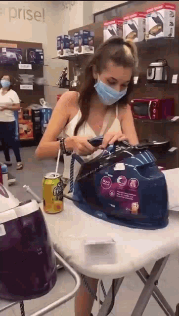 a woman wearing a face mask is sitting at an ironing board in a store