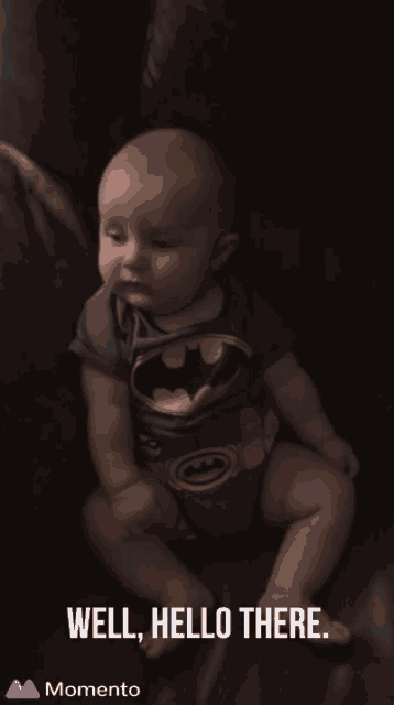 a baby in a batman outfit is sitting on a couch
