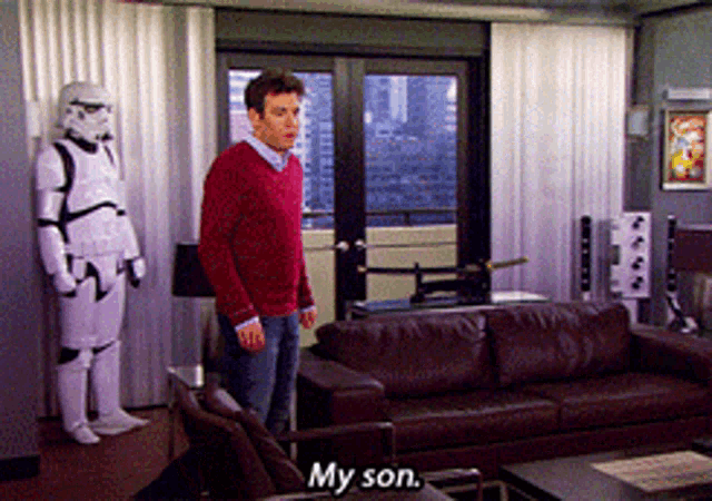 a man in a storm trooper costume stands in a living room next to a brown couch