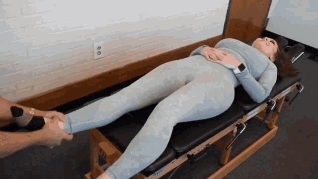 a woman is laying on a table with her legs crossed and a watch on her wrist