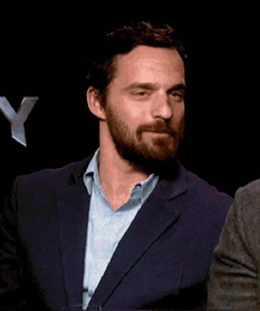 a man with a beard is wearing a blue jacket and a blue shirt