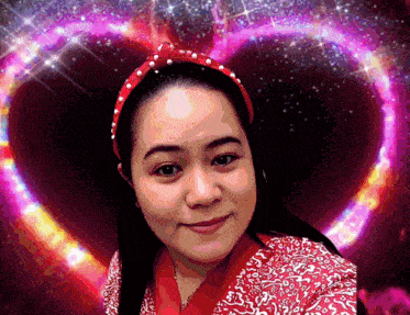 a woman wearing a red headband is smiling in front of a heart