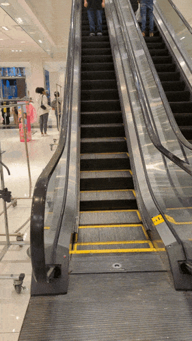 an escalator with a yellow stripe on the bottom of the stairs