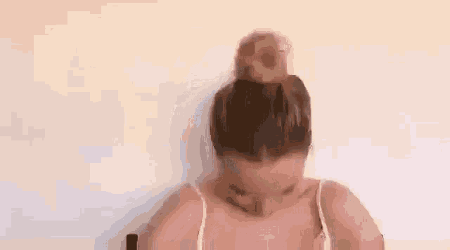 a woman with her hair in a bun is sitting in a chair and making a funny face .