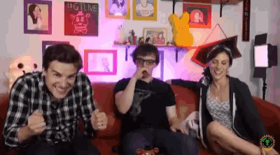three people sitting on a couch with a sign that says #gitlive on the wall behind them