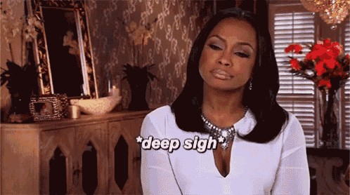 a woman in a white shirt says " deep sigh " while sitting in a living room