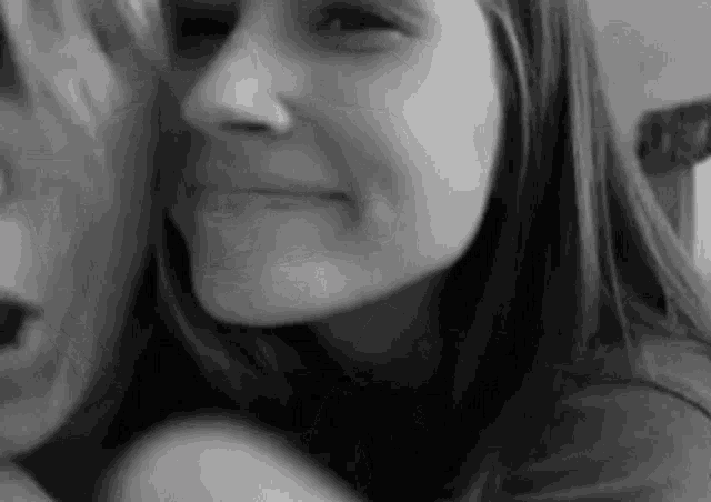 a close up of a woman 's face with a man 's face in the background