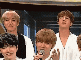 a group of young men are standing next to each other and a man is holding a microphone .