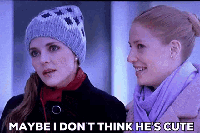 two women are standing next to each other and one of them is wearing a beanie .