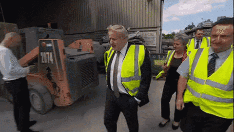 a man in a yellow vest stands in front of a forklift that says 2714