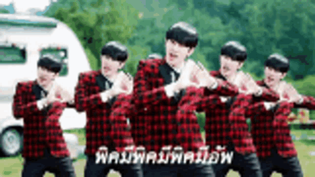 a group of men in plaid shirts are dancing in front of a camper .