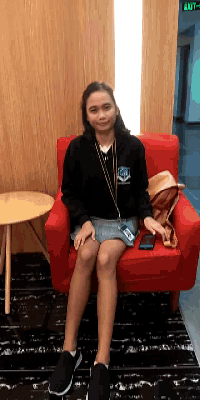 a girl is sitting in a red chair with a green exit sign behind her
