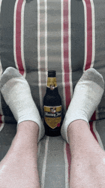 a bottle of hertog jan sits on a striped couch