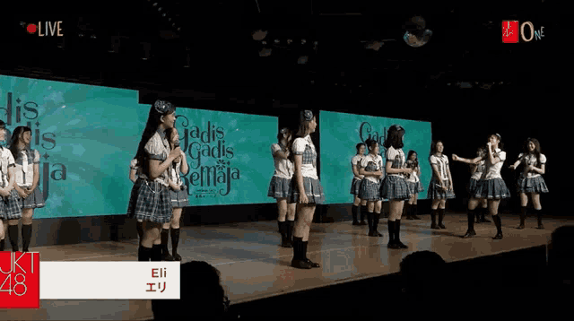 a group of girls are standing on a stage in front of a large screen that says gadis gadis kemaja