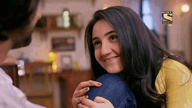a woman is sitting on a man 's lap and smiling while looking at him .