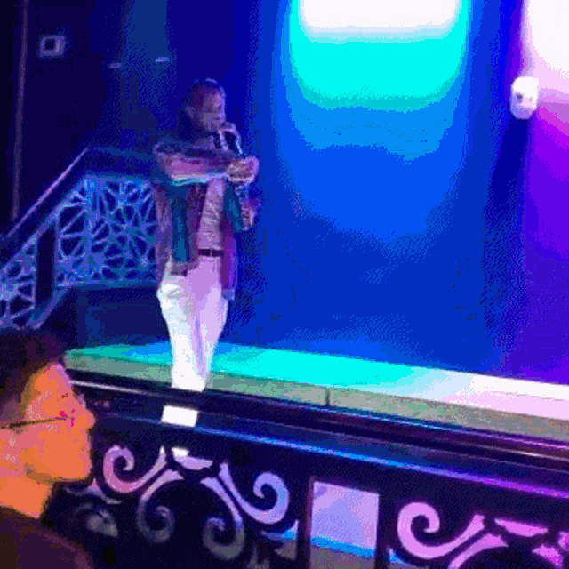 a man playing a saxophone on a stage in front of a blue light