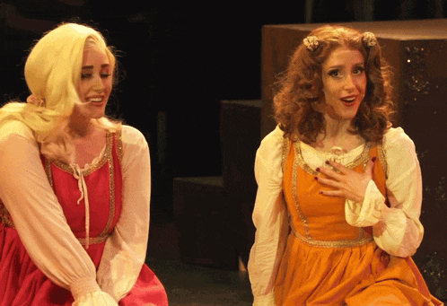 a woman in a red dress and a woman in an orange dress are sitting next to each other