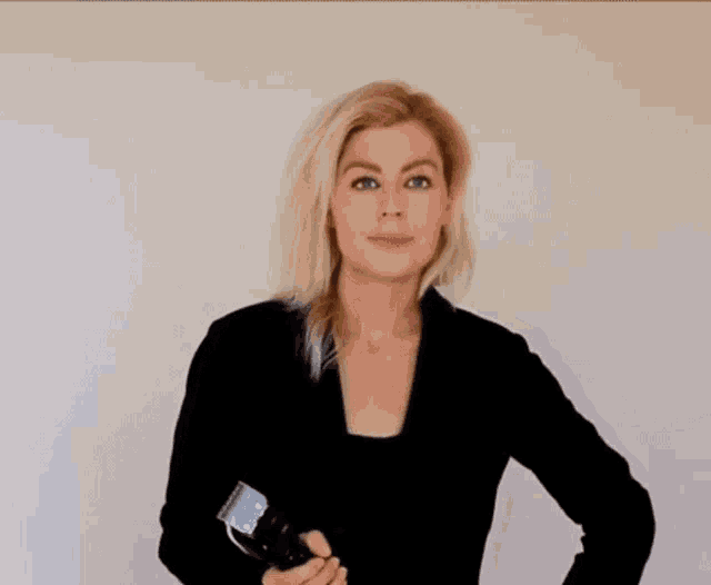 a woman in a black sweater is holding a hair clipper in her hand .