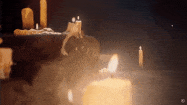 a bunch of lit candles are on a table in a dark room .