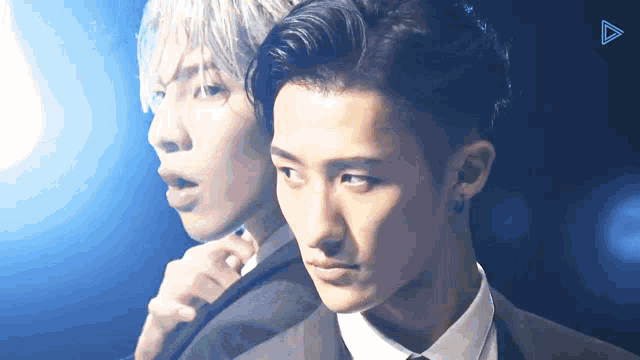 a man in a suit and tie is standing next to another man in a white shirt