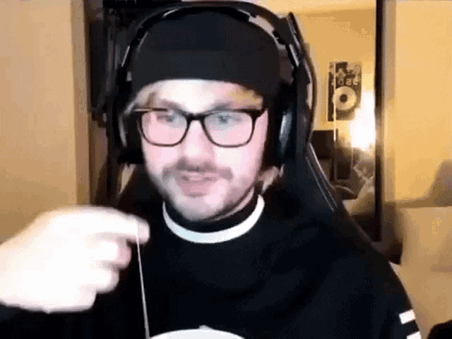 a man wearing glasses and headphones is sitting in a chair in a living room .