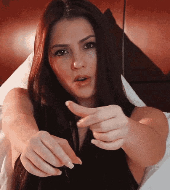 a woman with long hair is pointing her finger at something