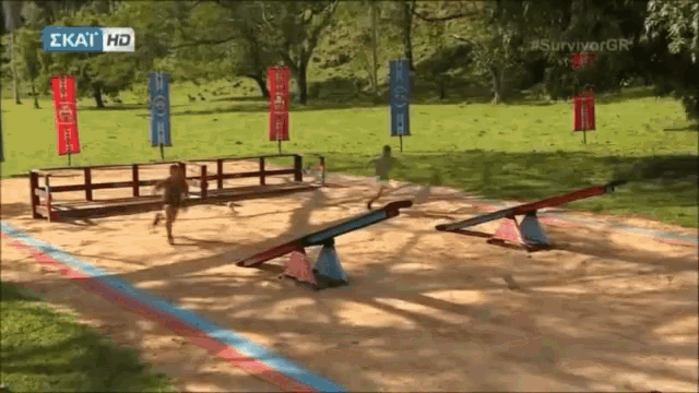 a group of people are playing on a seesaw in a park with a sign that says ' ekay hd ' on it