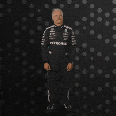 a man in a petronas suit stands in front of a dark background