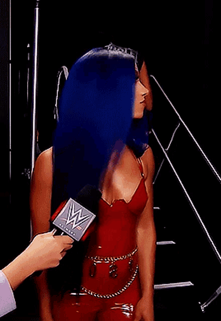 a woman in a red dress is being interviewed by a person with a microphone that says wwe on it