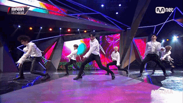 a group of men are dancing on a stage with a sign that says mama on it