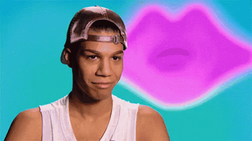 a young man wearing a baseball cap and a tank top is making a funny face in front of a pink lip .