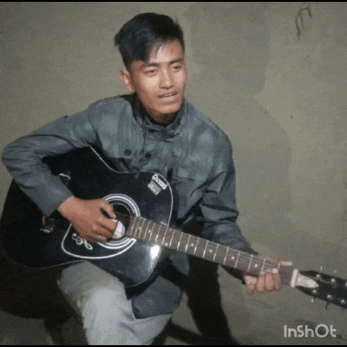 a young man is playing a black guitar with a sticker on the neck that says ' oasis '