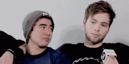 two men are sitting next to each other and one of them is wearing a beanie
