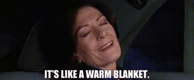 a woman is laying down with her eyes closed and the words `` it 's like a warm blanket '' written below her .