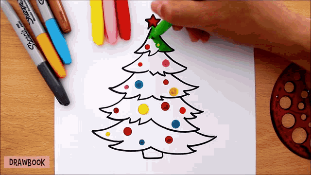 a person is drawing a christmas tree on a piece of paper with markers that say drawbook
