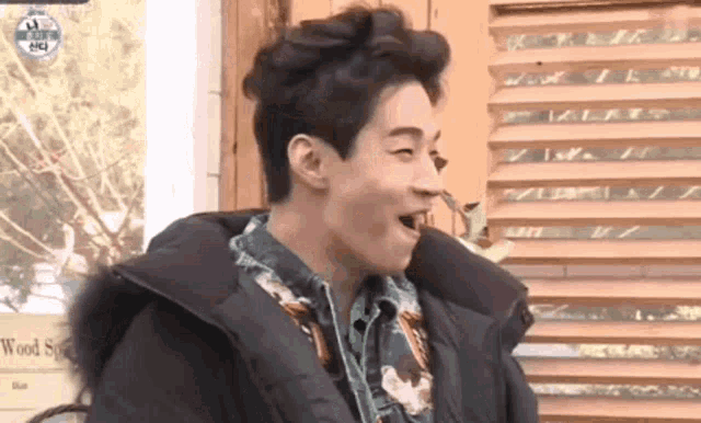 a man is making a funny face in front of a window with the word sun on it
