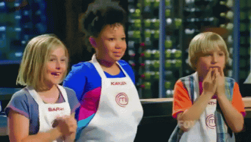 three children wearing aprons with the letter m on them are clapping