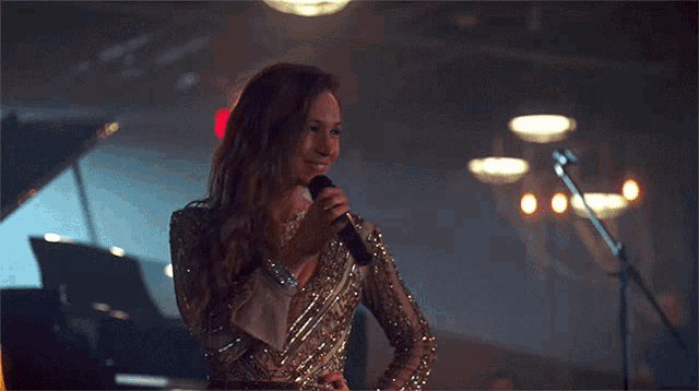 a woman sings into a microphone in a dark room