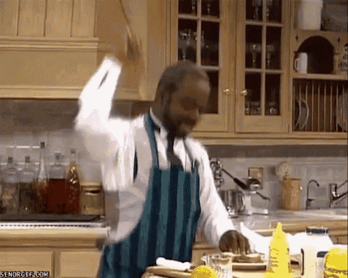 a man in an apron is standing in a kitchen with a bottle of mustard in front of him