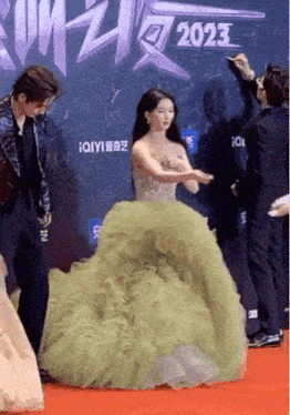 a woman in a green dress is standing on a red carpet in front of a wall with the year 2023 on it