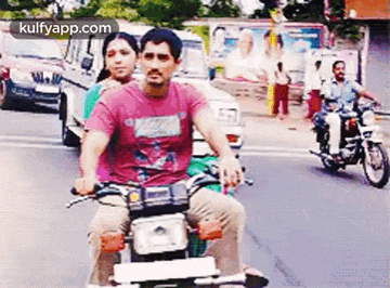 a man is riding a motorcycle with a woman sitting on the back .