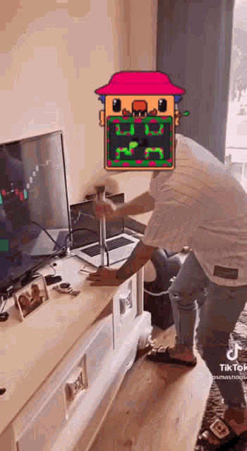 a man is holding a hammer in front of a tv while wearing a house mask .