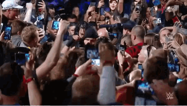 a crowd of people taking pictures with their cell phones with a w logo in the background