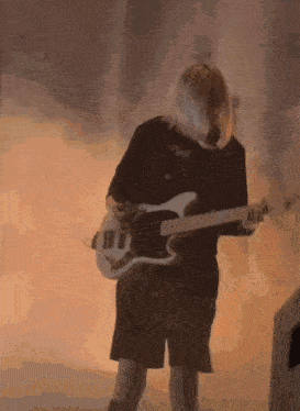a woman is playing a bass guitar on a stage in front of a fire .