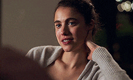a woman in a white sweater holds her hand to her face