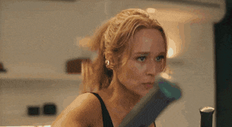 a woman in a black and blue tank top is holding a black object in her hand