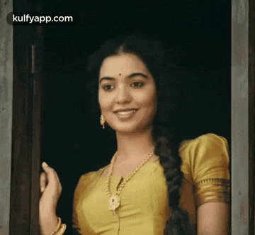 a woman in a yellow dress is standing in a doorway smiling .