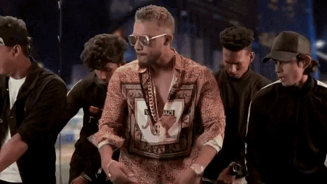 a group of men are standing around a man wearing sunglasses and a shirt that says mc on it