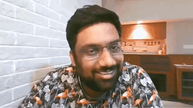 a man with glasses and a flamingo shirt is smiling